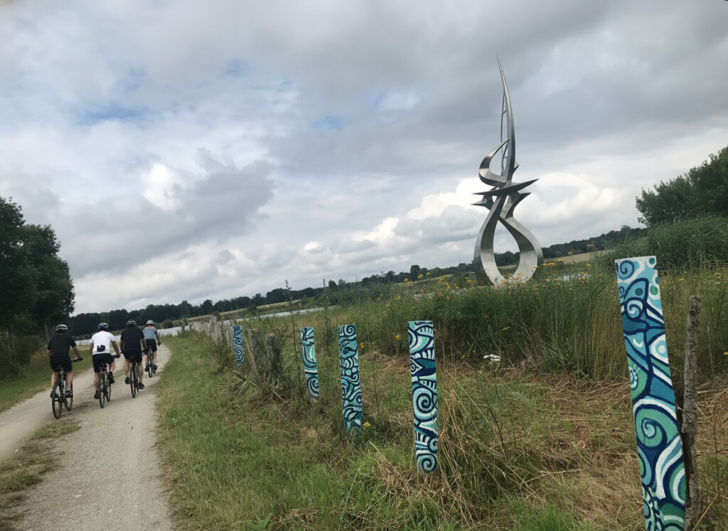 Beispielhafte Darstellung einer Radtour entlang von gestalteten Stelen und einer großen abstrakten Metallskulptur am Elbe-Havel-Kanal.